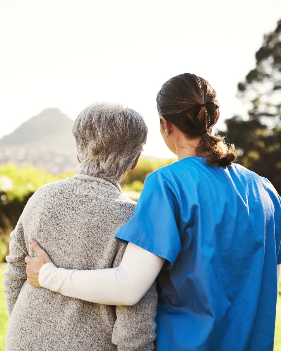 Caregiver and senior woman enjoying a walk outdoors together