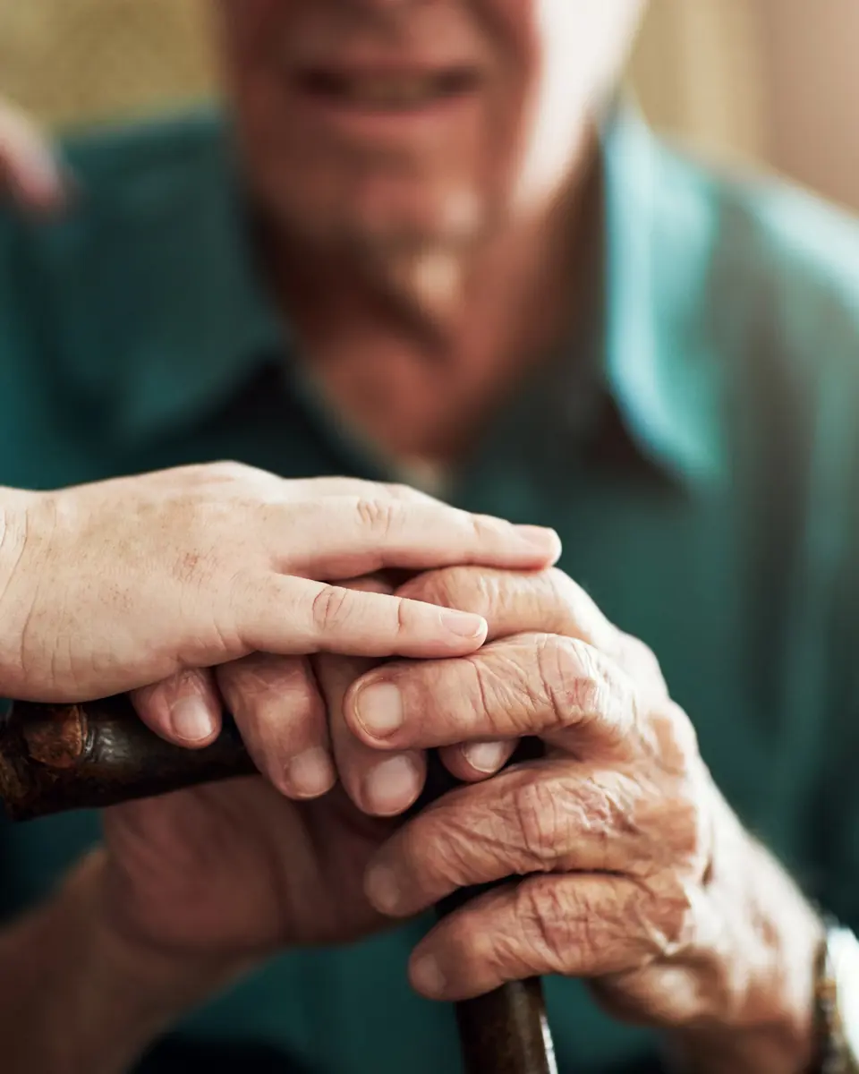 Caregiver gently holding the hands of an older man